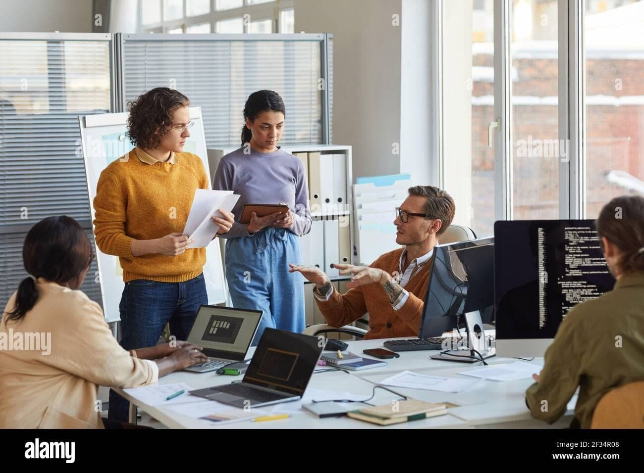 Portrait of diverse software development team collaborating on project in  modern office, focus on lead engineer inst…